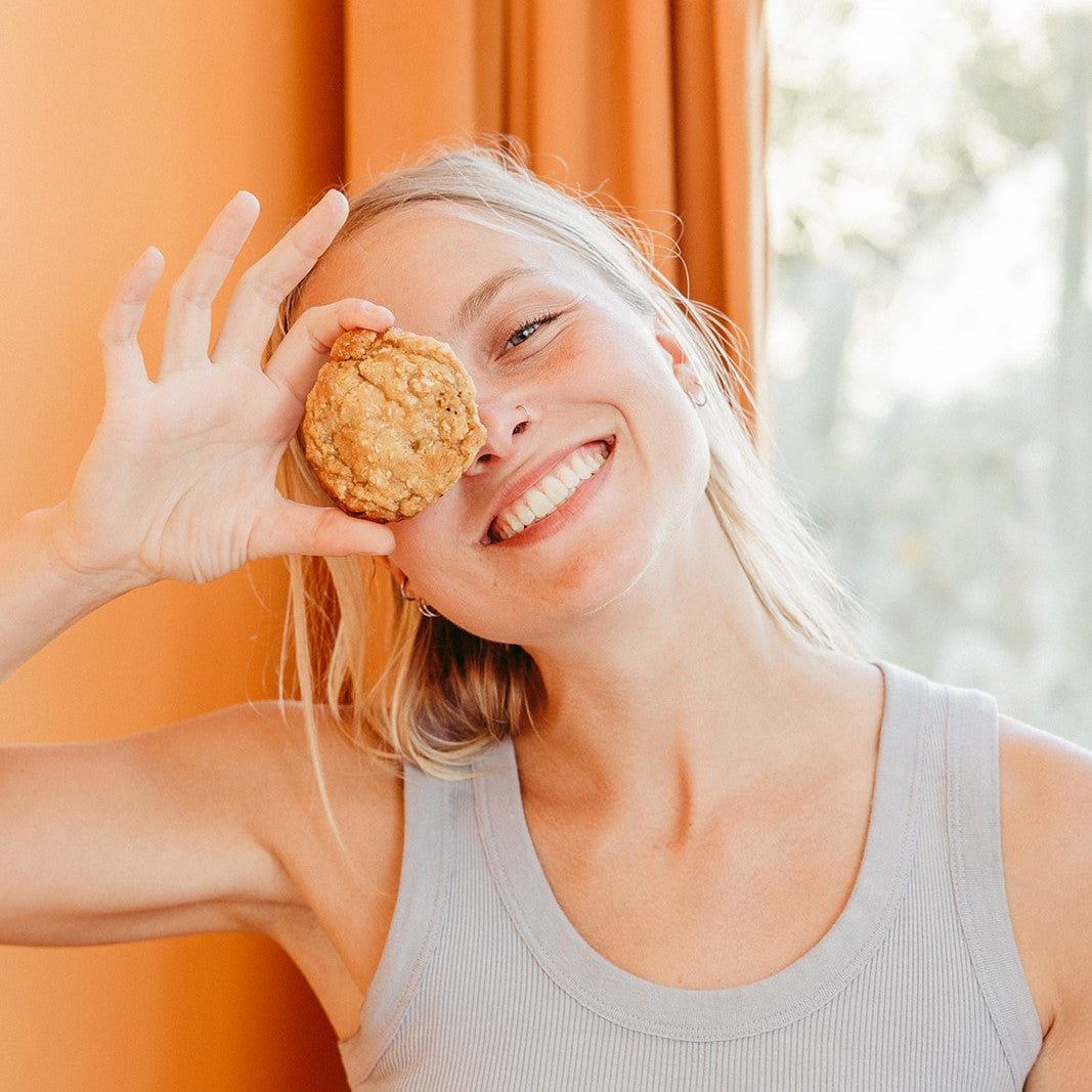 A smiling girl holding a gooey Oatmeal Toffee cookie